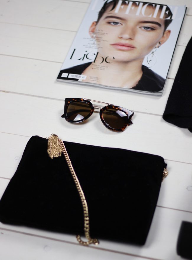 schwarze Handtasche, Sonnenbrille, Zeitschrift